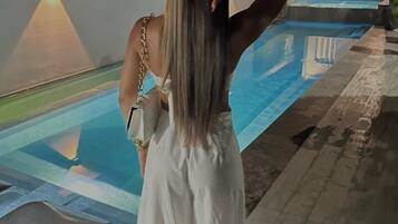 Una persona de pie junto a una piscina por la noche.