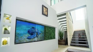Een muur met een groot ingelijst beeld van een blauwe zeeschildpad, een klein Boeddhabeeldje, en een ander ingelijst beeld erboven.