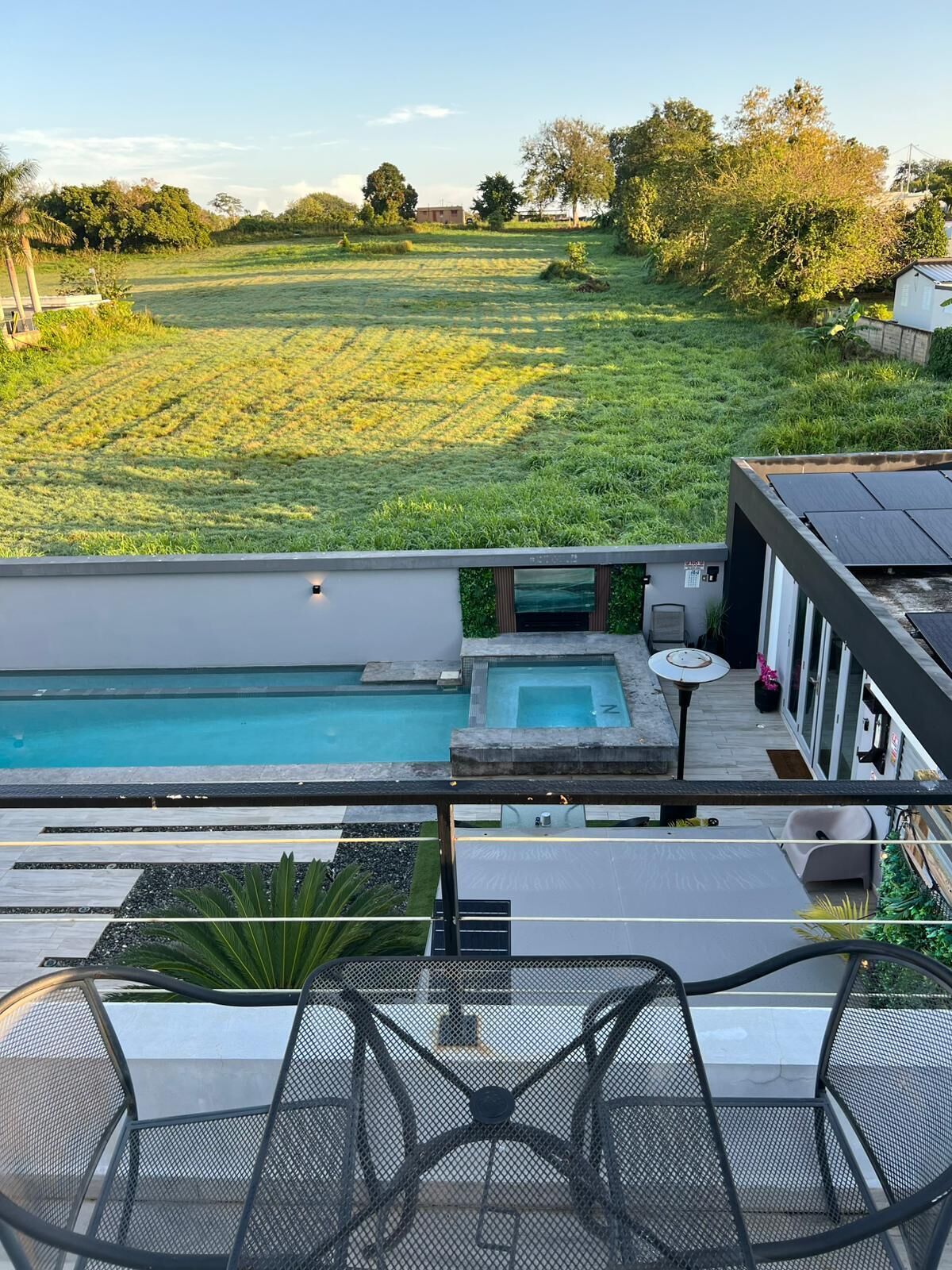 Une piscine sur le toit offrant une vue sur un champ verdoyant et des arbres.