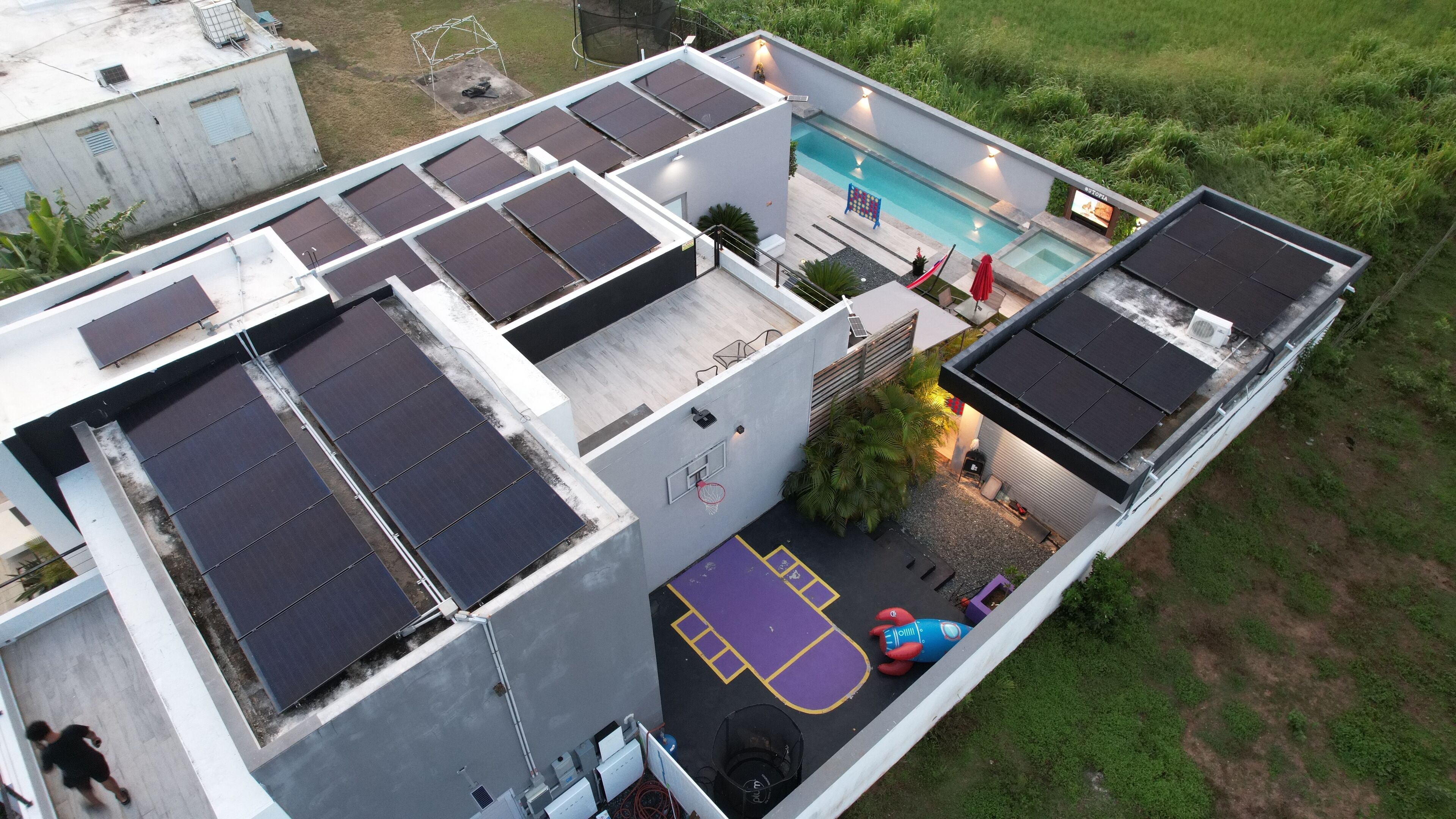 A rooftop with solar panels, a swimming pool, and a basketball court.