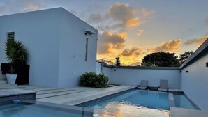 Een modern zwembadgedeelte buiten, met een heldere lucht en zonsondergang.