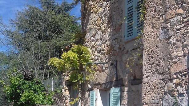 Un edificio rústico de piedra con un camino de grava que lleva a la entrada.