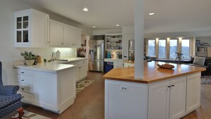 A modern kitchen with white cabinetry, a wooden countertop, and a built-in island. - Beautiful French Inspired Country Home Super Private River Views (Gambier)