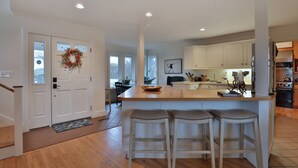 A spacious kitchen with a large island, white cabinets, and a view to the dining area. - Beautiful French Inspired Country Home Super Private River Views (Gambier)