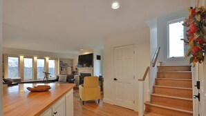 A spacious kitchen with a wooden countertop, a yellow armchair, and a staircase leading to another level. - Beautiful French Inspired Country Home Super Private River Views (Gambier)