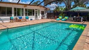 A covered swimming pool with lounge chairs and a patio area.