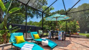 An outdoor patio with lounge chairs, a table, and an umbrella.