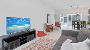 A living room with a flat-screen TV, a gray sofa, and a patterned rug.