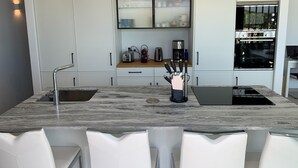Una cocina moderna con armarios blancos, encimera de mármol y horno empotrado.