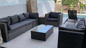 Un patio en la azotea con un sofá modular, dos sillones y una mesa de centro.