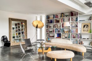 Un salon moderne avec une grande bibliothèque, un canapé, une table basse et un miroir.