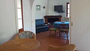 Uma sala de estar com área de jantar, lareira e televisão.