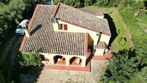 Uma casa de dois andares com telhado de telhas, base de pedra e um pequeno jardim.