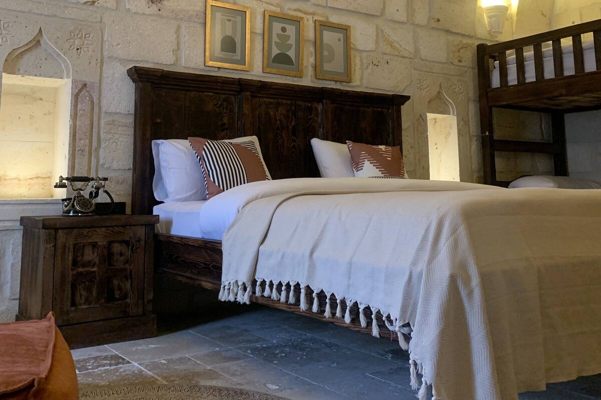 A rustic room with a stone wall, wooden bed, and a vintage telephone.