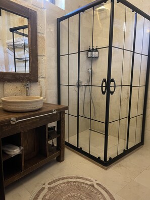A bathroom with a wooden vanity, a round sink, a glass shower enclosure, and a tiled floor. - Nujel'm Cappadocia (Ürgüp)