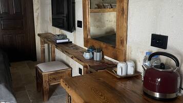 A rustic kitchen with a wooden counter, a kettle, and a mirror.