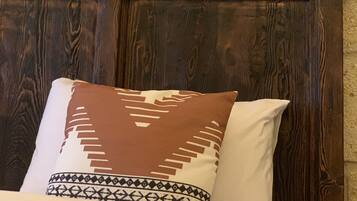 A bed with a patterned pillow and a plain pillow, a wooden headboard, and two framed pictures on the wall.