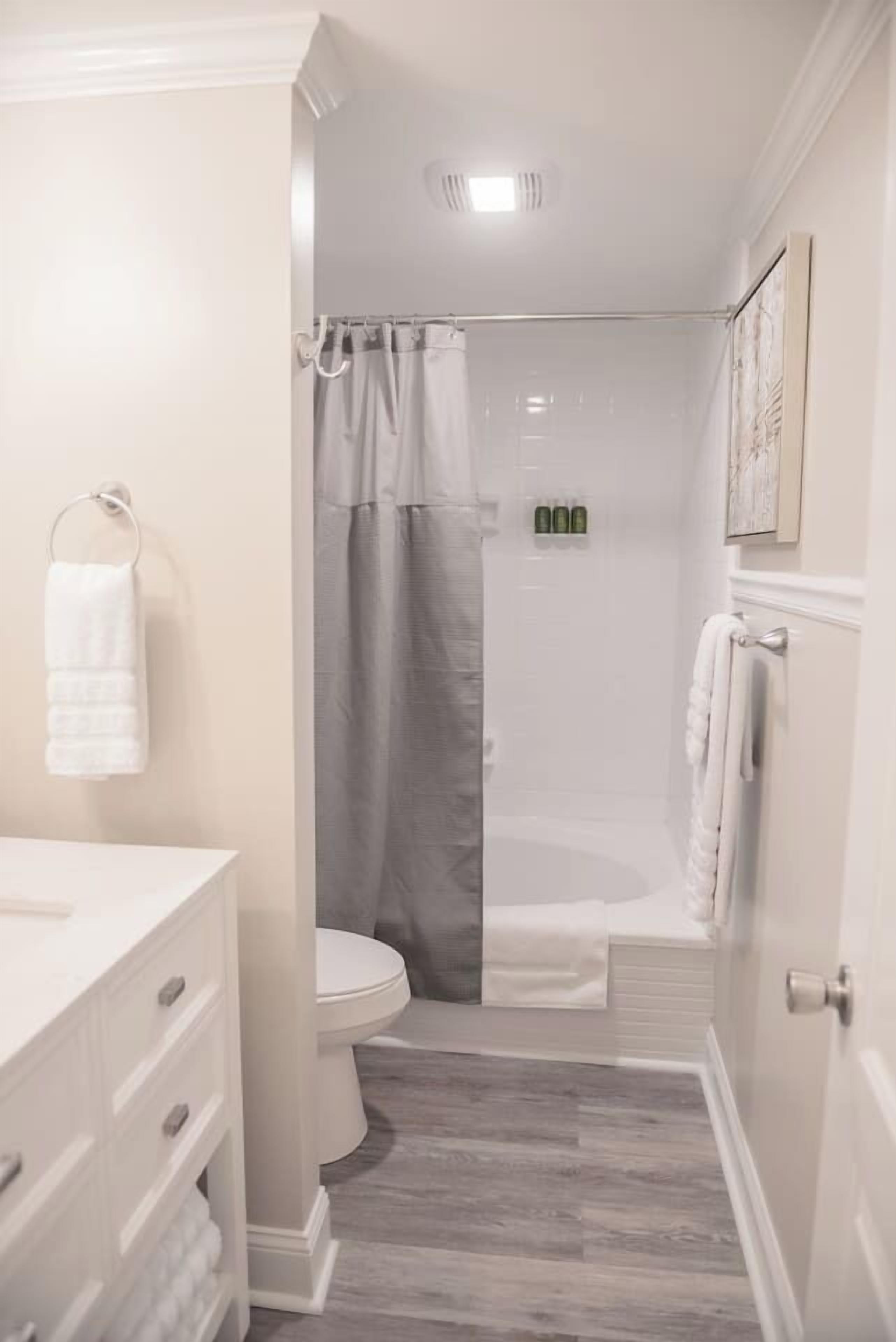 A bathroom with a shower, toilet, and vanity with drawers.