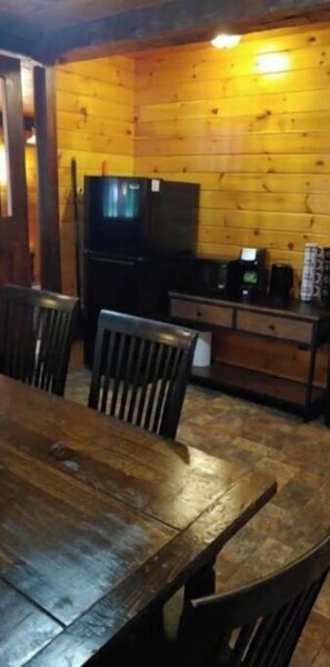 Enjoy meals in this cozy dining area with a table, chairs, and kitchenette featuring a refrigerator and microwave.