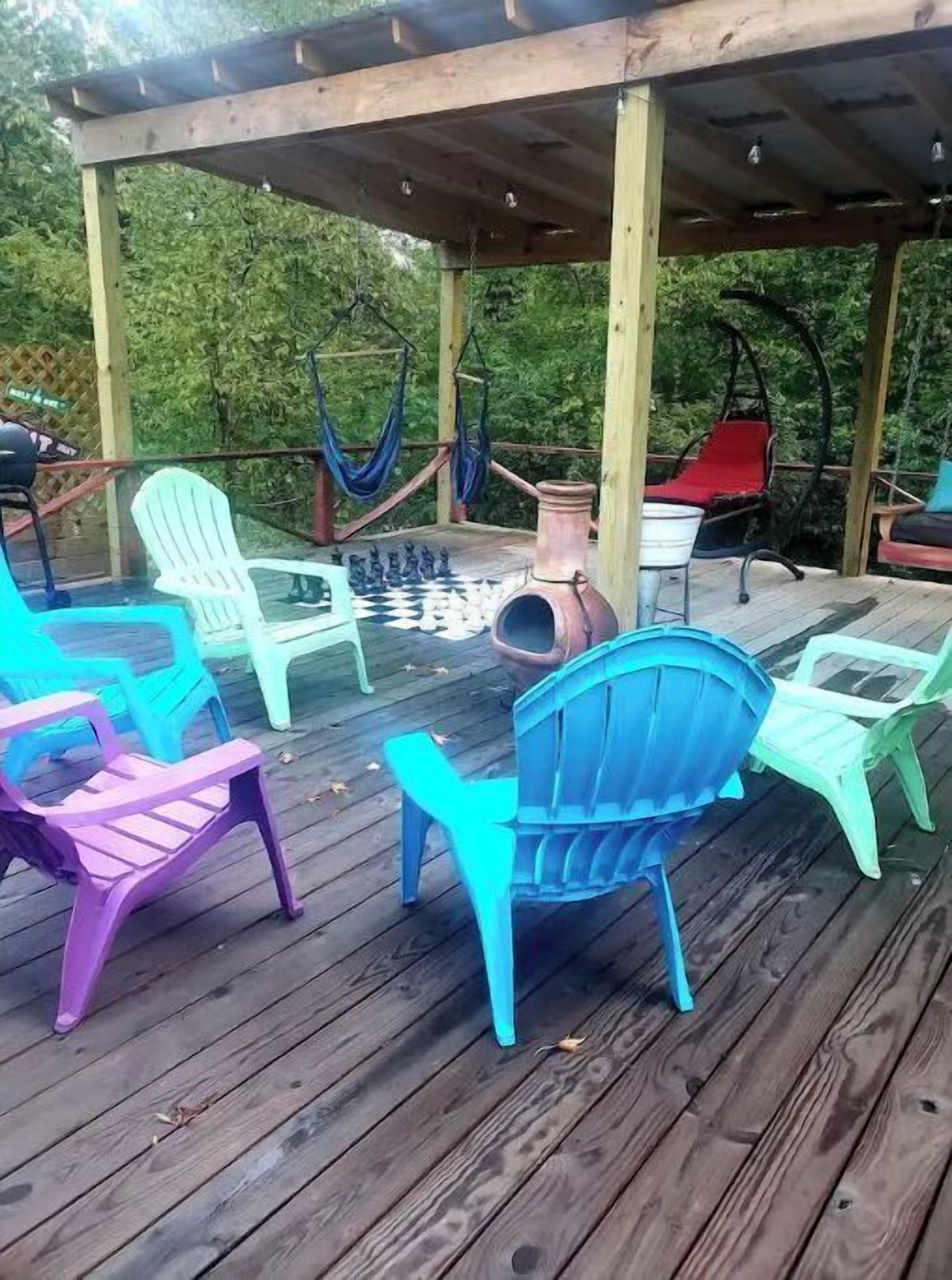 A wooden deck with colorful plastic chairs and a hanging hammock.