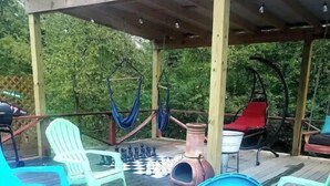 Une terrasse en bois avec des chaises en plastique de couleurs vives et un hamac suspendu.