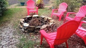 Un foyer extérieur entouré de chaises rouges, dans un jardin.