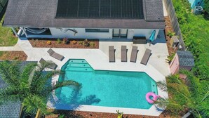 A modern house with a swimming pool, a covered patio, and a solar panel on the roof.
