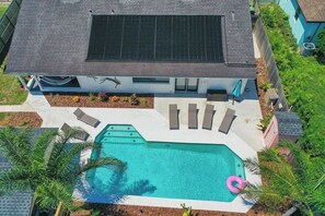 Une maison moderne dotée d’une piscine, d’un patio couvert et d’un panneau solaire sur le toit.