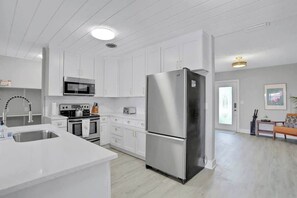 Una cocina moderna con armarios blancos, electrodomésticos de acero inoxidable y una isla central.
