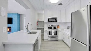 A modern kitchen with white cabinetry, stainless steel appliances, and a central island.