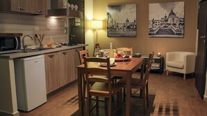A modern kitchen with a dining area, wooden cabinets, a microwave, and a dining table set for two. - Cozy apartment in the heart of the historic center of Palermo (Palermo)