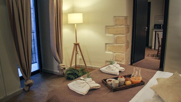 A hotel room with a bed, a bedside table with a tray of breakfast items, a lamp, and a view of the hallway. - Cozy apartment in the heart of the historic center of Palermo (Palermo)