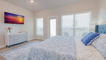 Um quarto com cama, cômoda, televisão e janela com persianas.