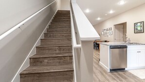 Una cucina moderna con una scala in legno, mobili bianchi e una lavastoviglie integrata.