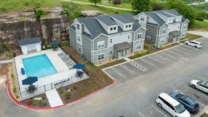Un edificio residenziale a più piani con piscina, parcheggio e vista sul paesaggio circostante.