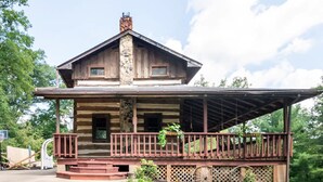 A log cabin with a porch and a covered area, surrounded by greenery. - Stunning Boho Log Cabin Country Retreat with Pool
 (Portland)