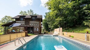A wooden cabin with a swimming pool, surrounded by trees. - Stunning Boho Log Cabin Country Retreat with Pool
 (Portland)