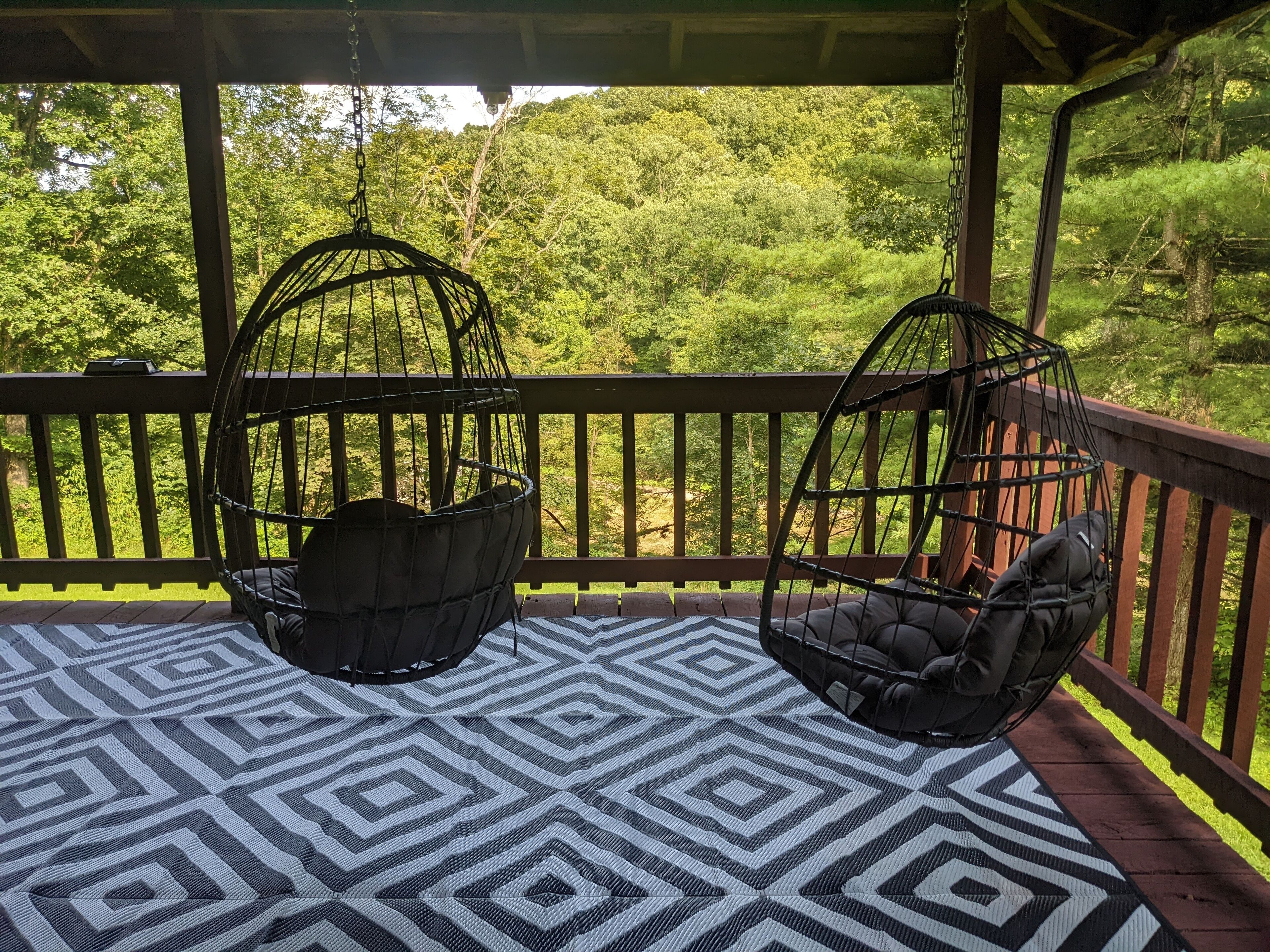 A covered outdoor seating area with two hanging chairs and a patterned floor.