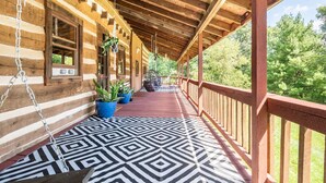 A log cabin with a covered porch, potted plants, and a patterned floor. - Stunning Boho Log Cabin Country Retreat with Pool
 (Portland)