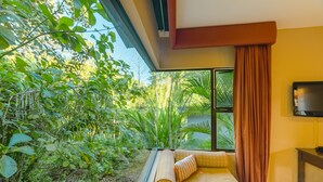 Una habitaci ón con un sofá frente a un amplio ventanal con vistas a un jardín exuberante.