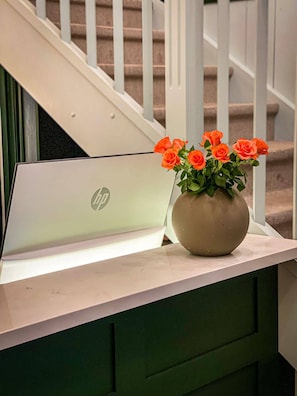 A laptop with an HP logo on a white surface, placed next to a vase with orange roses.