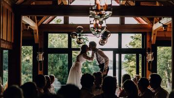 A couple kissing in a rustic wooden room with large windows and hanging light fixtures.