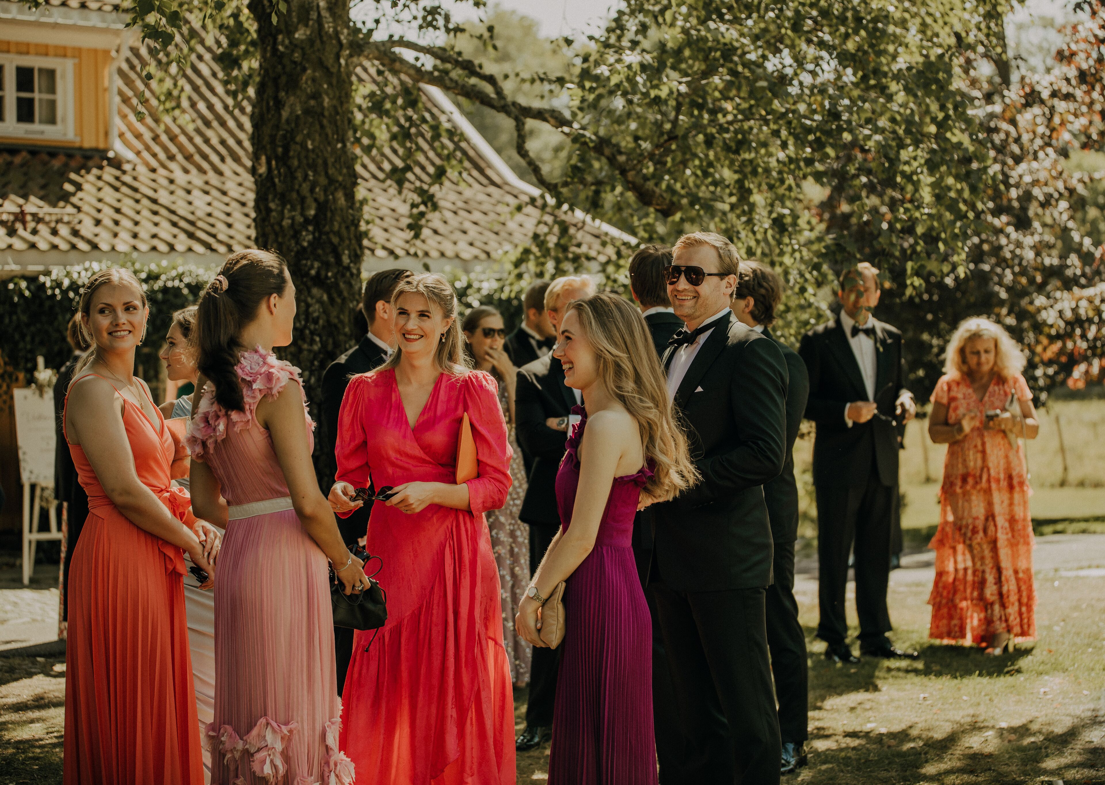 Un grupo de personas con vestimenta formal al aire libre, posiblemente en una boda o evento formal.