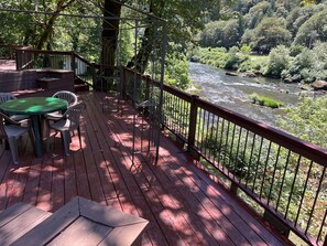Une terrasse en bois avec une table et des chaises, donnant sur une rivière.