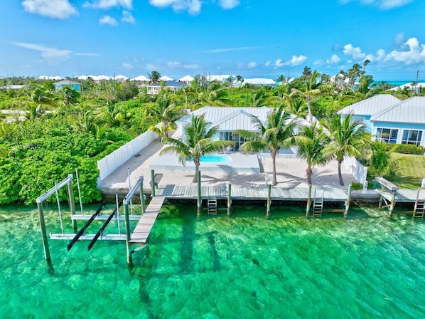 A resort with a pool area, palm trees, and clear turquoise water.