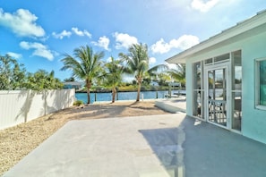 A waterfront property with a concrete patio, palm trees, and a building with large windows.