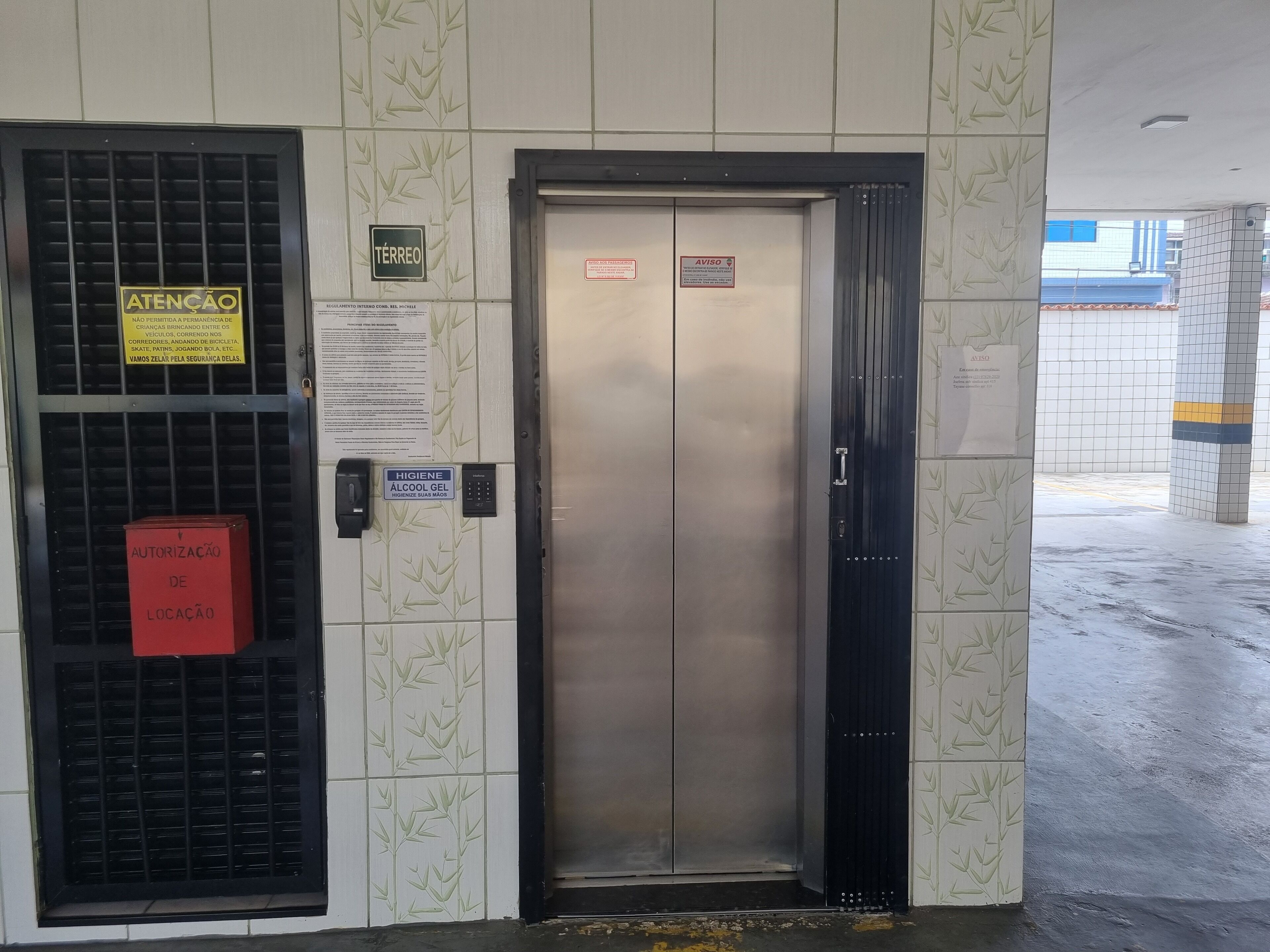 An elevator with a security keypad and a sign indicating 'ATENÇÃO' (Attention).