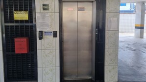 An elevator with a security keypad and a sign indicating 'ATENÇÃO' (Attention). - Kitnet na Cidade Ocian / Praia Grande (Praia Grande)