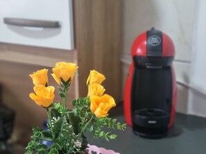Cozinha com cafeteira e um buquê de rosas amarelas.