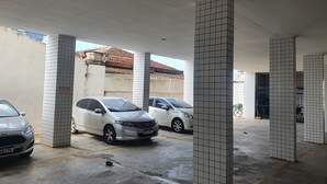 A parking garage with tiled pillars and two parked cars. - Kitnet na Cidade Ocian / Praia Grande (Praia Grande)